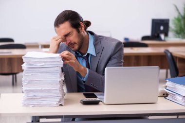 Ofisteki aşırı işten memnun olmayan genç bir erkek işçi.