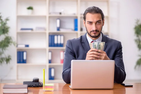 Jonge mannelijke werknemer met bankbiljetten in het kantoor — Stockfoto