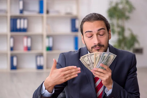 Jonge mannelijke werknemer met bankbiljetten in het kantoor — Stockfoto