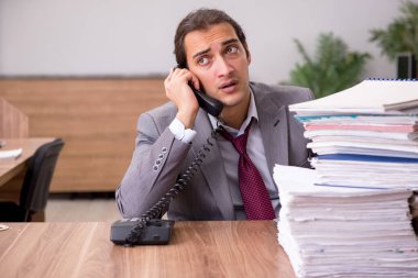 Ofisteki aşırı işten memnun olmayan genç bir erkek işçi.