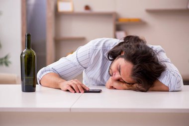 Genç adam evde alkol içiyor.