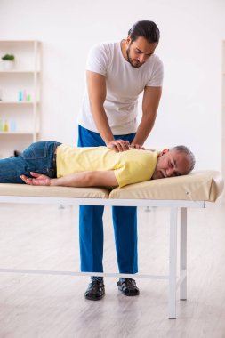 Yaşlı erkek hasta, genç erkek doktor masörünü ziyaret ediyor.