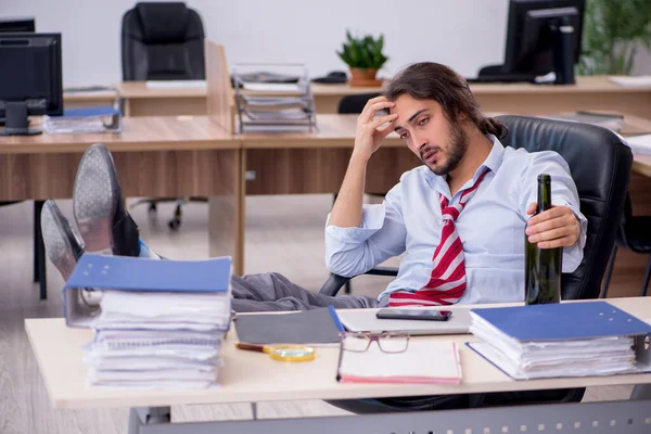 Jonge mannelijke werknemer drinkt alcohol op kantoor — Stockfoto