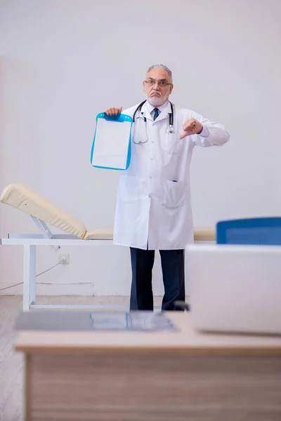 Gammal manlig läkare som arbetar på kliniken — Stockfoto