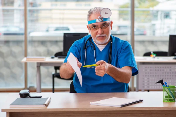 Starý mužský lékař laryngolog pracující na klinice — Stock fotografie