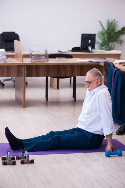 Old businessman employee doing sport exercises in the office — Stock Photo, Image