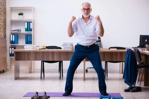 Old businessman employee doing sport exercises in the office — Stock Photo, Image