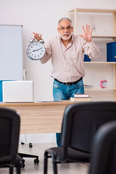 Antigo professor do sexo masculino em sala de aula no conceito de gestão do tempo — Fotografia de Stock