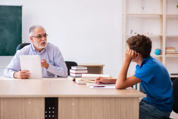 Oude mannelijke leraar en schooljongen in de klas — Stockfoto