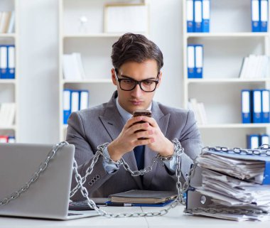 Ofis masasına zincirlenmiş meşgul bir çalışan.