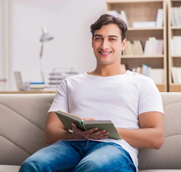 Man die het boek leest zittend op de bank — Stockfoto