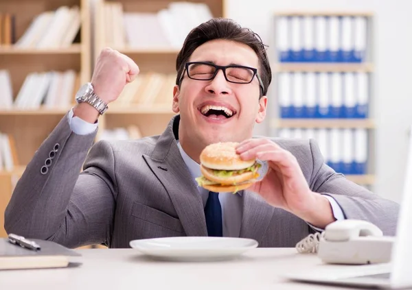 Hambriento empresario divertido comer sándwich de comida chatarra — Foto de Stock