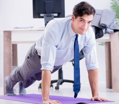 İş adamı tatilde ofiste spor yapıyor.