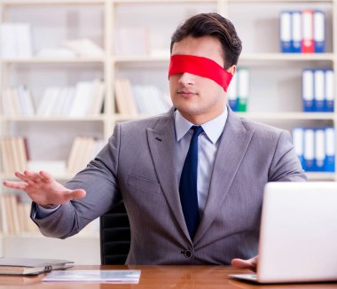 Ofiste masasında oturan gözü bağlı iş adamı.