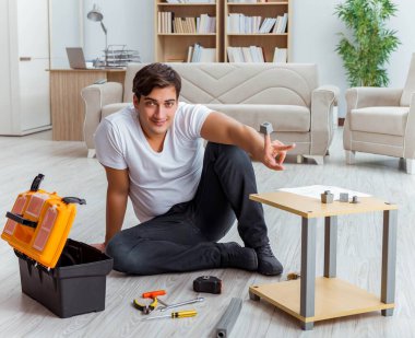 Adam evde mobilya montajı yapıyor.