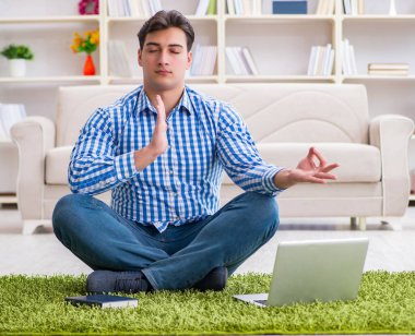 Genç yakışıklı adam evde yerde oturuyor.