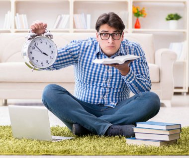 Genç yakışıklı adam evde yerde oturuyor.