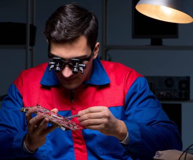 Bilgisayar uzmanı gece geç saatlerde bilgisayarı tamir ediyor.