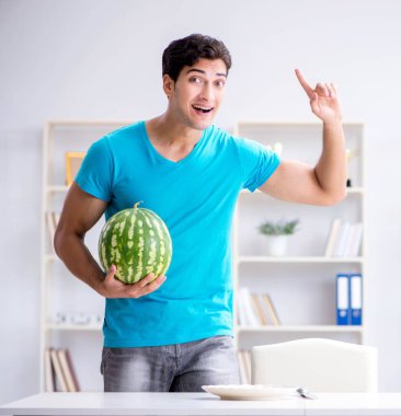 Evde karpuz yiyen bir adam.