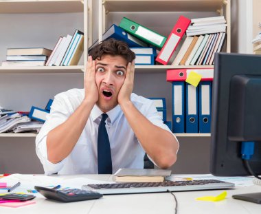 Ofiste kitap ve kağıtlarla çalışan bir işadamı.