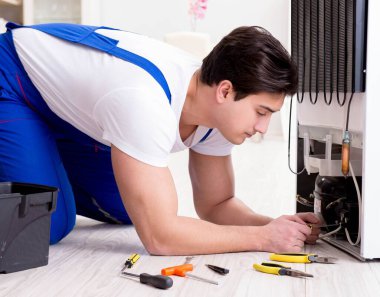 Tamirci müteahhit DIY konseptinde buzdolabını tamir ediyor.