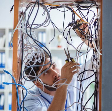 Elektrik teknisyeni tamir konseptinde kabloları çözmeye çalışıyor.
