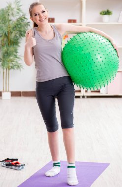 Spor salonunda denge topuyla egzersiz yapan genç bir kadın.