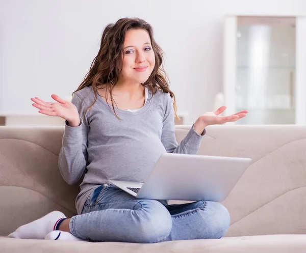 Mulher grávida trabalhando no laptop sentado no sofá — Fotografia de Stock