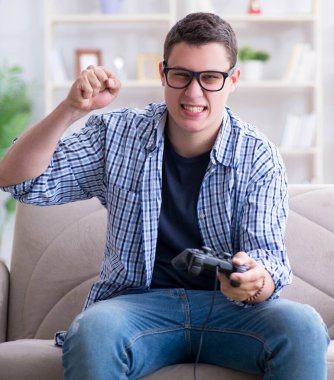 Genç adam evde bilgisayar oyunu oynuyor.