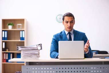 Ofisteki aşırı işten memnun olmayan genç bir erkek işçi.