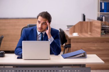 Genç adam işyerinde oturuyor.