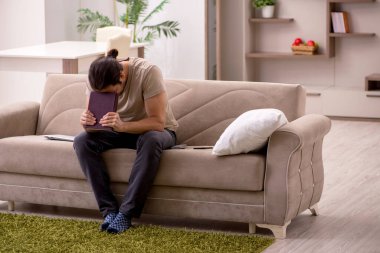 Evde kitap okuyan genç bir erkek öğrenci.