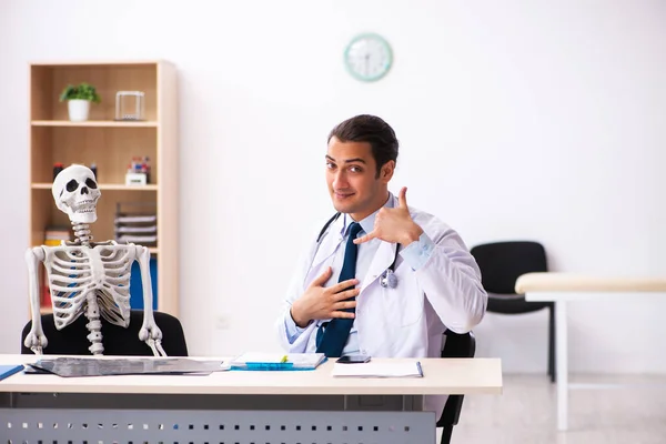 Jonge mannelijke arts en skelet patiënt in de kliniek — Stockfoto