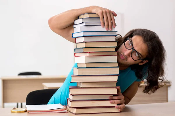 Giovane studente maschio e un sacco di libri in classe — Foto Stock