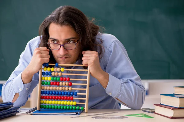 Young male teacher in front of green board