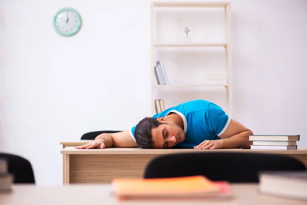 Estudante masculino exausto se preparando para os exames em sala de aula — Fotografia de Stock