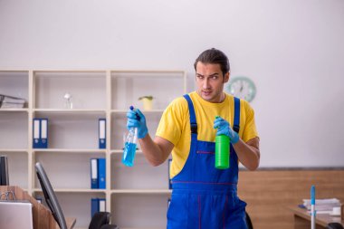 Genç müteahhit ofisi temizliyor.