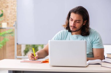 Genç erkek öğrenci tele-eğitim konsepti sınavlarına hazırlanıyor.