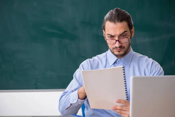 Jonge mannelijke leraar in het klaslokaal in teleonderwijsconcept — Stockfoto