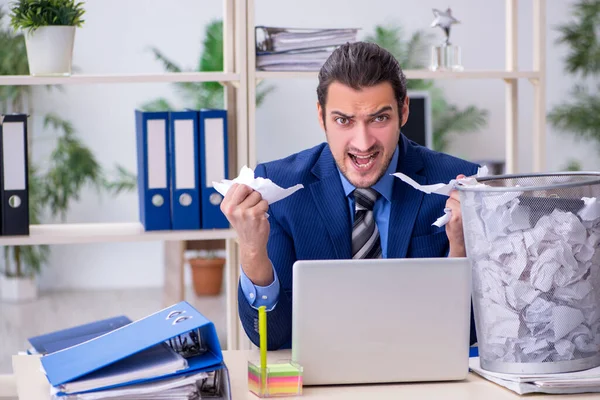 Empleado joven de negocios rechazando nuevas ideas con un montón de pape —  Fotos de Stock