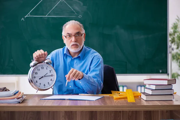 Oude mannelijke wiskundeleraar in tijdmanagementconcept — Stockfoto