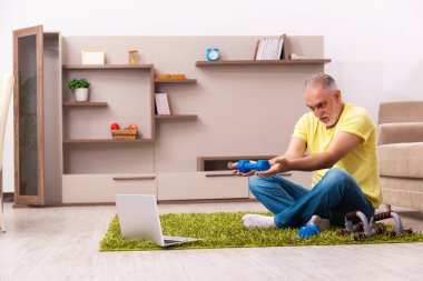 Yaşlı adam evde spor egzersizleri yapıyor.