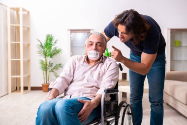 Tekerlekli sandalyedeki yaşlı adam ve genç kötü bakıcı.