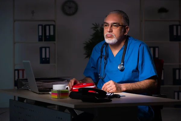 Aged male doctor in the hospital at night — Stock Photo, Image