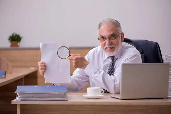 Velho funcionário do sexo masculino leitura de papel no escritório — Fotografia de Stock