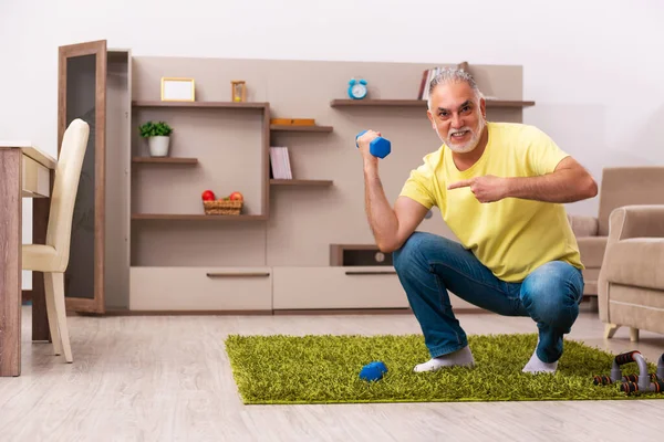 У віці чоловік робить спортивні вправи вдома — стокове фото