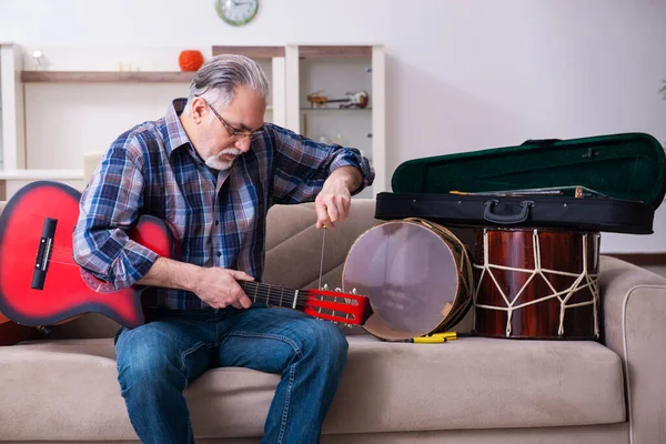 Riparatore anziano di sesso maschile che ripara strumenti musicali a casa — Foto Stock