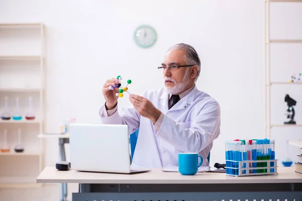 Oude mannelijke wetenschapper die moleculair model bestudeert — Stockfoto