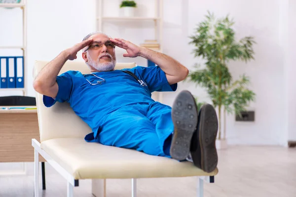 Vecchio medico di sesso maschile estremamente stanco dopo il turno di notte — Foto Stock