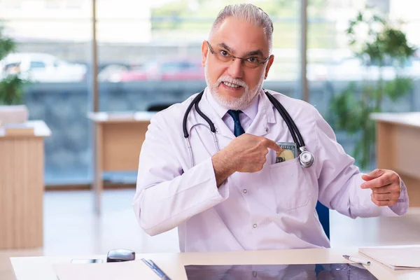 Viejo doctor en concepto de remuneración —  Fotos de Stock